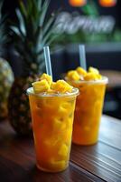 Pineapple juice in plastic cups and pineapple on the table photo