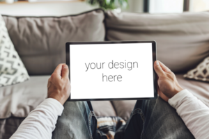 Tablet mockup. Person sits on sofa in room and holds tablet in front of him. psd