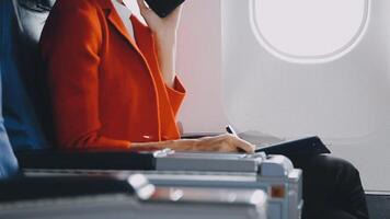 Attractive asian female passenger of airplane sitting in comfortable seat listening music in earphones while working at modern laptop computer with mock up area using wireless connection on board. video
