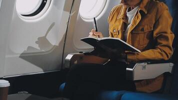 Attractive asian female passenger of airplane sitting in comfortable seat listening music in earphones while working at modern laptop computer with mock up area using wireless connection on board. video