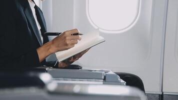 Attractive asian female passenger of airplane sitting in comfortable seat listening music in earphones while working at modern laptop computer with mock up area using wireless connection on board. video
