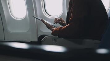 Woman hand using smart phone on airplane. Female traveler using smart phone in passenger cabin. Can be add your texts or others on screen. Sun shining trough airplane window. Technology concept. video