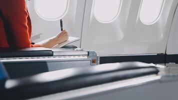 Attractive asian female passenger of airplane sitting in comfortable seat listening music in earphones while working at modern laptop computer with mock up area using wireless connection on board. video