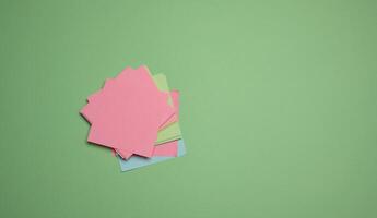 Stack of paper blank stickers on green background, top view photo