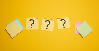 Drawn question marks on stickers, yellow background. Searching for truth photo