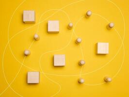 Wooden figures of men and a trajectory between obstacles on a yellow background photo