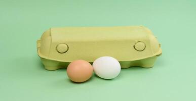 Two chicken eggs in a paper box on a green background photo