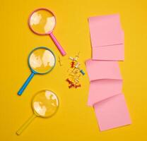 Plastic magnifying glass and empty paper stickers on yellow background photo