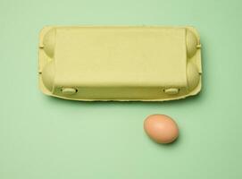 Chicken egg and paper storage box on green background, top view photo