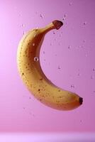 Banana in mid-air with refreshing water droplets against a pink backdrop photo