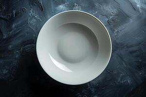 An empty white plate awaits a culinary creation, set against a dark textured backdrop photo
