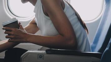 Attractive asian female passenger of airplane sitting in comfortable seat listening music in earphones while working at modern laptop computer with mock up area using wireless connection on board. video