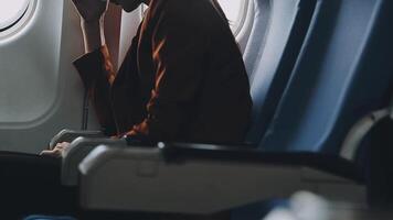 Attractive asian female passenger of airplane sitting in comfortable seat listening music in earphones while working at modern laptop computer with mock up area using wireless connection on board. video