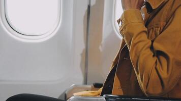 Woman hand using smart phone on airplane. Female traveler using smart phone in passenger cabin. Can be add your texts or others on screen. Sun shining trough airplane window. Technology concept. video