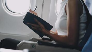Attractive asian female passenger of airplane sitting in comfortable seat listening music in earphones while working at modern laptop computer with mock up area using wireless connection on board. video