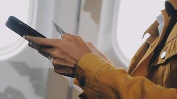 Woman hand using smart phone on airplane. Female traveler using smart phone in passenger cabin. Can be add your texts or others on screen. Sun shining trough airplane window. Technology concept. video