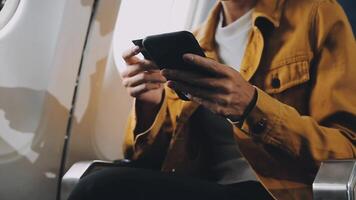 Woman hand using smart phone on airplane. Female traveler using smart phone in passenger cabin. Can be add your texts or others on screen. Sun shining trough airplane window. Technology concept. video
