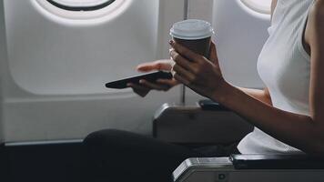 Woman hand using smart phone on airplane. Female traveler using smart phone in passenger cabin. Can be add your texts or others on screen. Sun shining trough airplane window. Technology concept. video