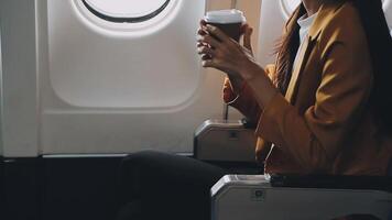 Attractive asian female passenger of airplane sitting in comfortable seat listening music in earphones while working at modern laptop computer with mock up area using wireless connection on board. video