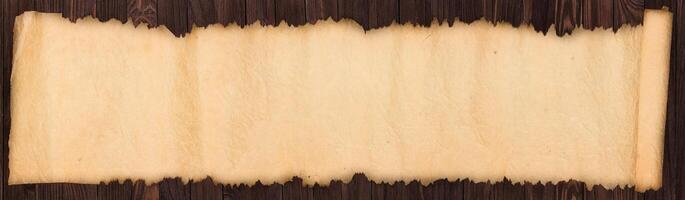 Old scroll on a wooden table, crumpled paper texture as background photo