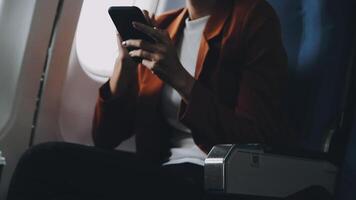 Woman hand using smart phone on airplane. Female traveler using smart phone in passenger cabin. Can be add your texts or others on screen. Sun shining trough airplane window. Technology concept. video
