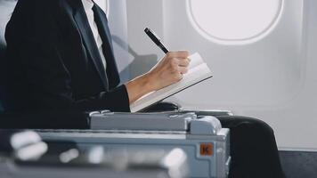 Attractive asian female passenger of airplane sitting in comfortable seat listening music in earphones while working at modern laptop computer with mock up area using wireless connection on board. video