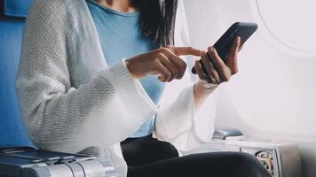 Woman hand using smart phone on airplane. Female traveler using smart phone in passenger cabin. Can be add your texts or others on screen. Sun shining trough airplane window. Technology concept. video