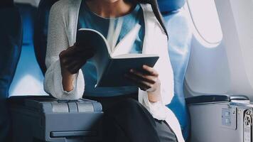 Attractive asian female passenger of airplane sitting in comfortable seat listening music in earphones while working at modern laptop computer with mock up area using wireless connection on board. video