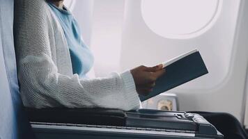 Attractive asian female passenger of airplane sitting in comfortable seat listening music in earphones while working at modern laptop computer with mock up area using wireless connection on board. video