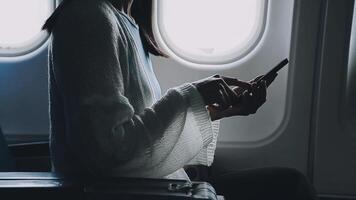 Woman hand using smart phone on airplane. Female traveler using smart phone in passenger cabin. Can be add your texts or others on screen. Sun shining trough airplane window. Technology concept. video