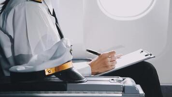 Attractive asian female passenger of airplane sitting in comfortable seat listening music in earphones while working at modern laptop computer with mock up area using wireless connection on board. video
