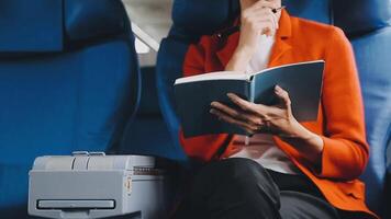 Attractive asian female passenger of airplane sitting in comfortable seat listening music in earphones while working at modern laptop computer with mock up area using wireless connection on board. video