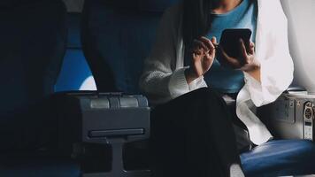 Woman hand using smart phone on airplane. Female traveler using smart phone in passenger cabin. Can be add your texts or others on screen. Sun shining trough airplane window. Technology concept. video