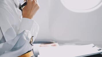 Attractive asian female passenger of airplane sitting in comfortable seat listening music in earphones while working at modern laptop computer with mock up area using wireless connection on board. video