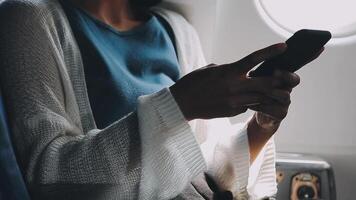 Woman hand using smart phone on airplane. Female traveler using smart phone in passenger cabin. Can be add your texts or others on screen. Sun shining trough airplane window. Technology concept. video