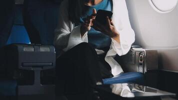 Woman hand using smart phone on airplane. Female traveler using smart phone in passenger cabin. Can be add your texts or others on screen. Sun shining trough airplane window. Technology concept. video