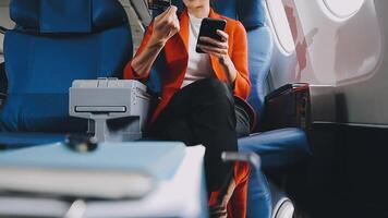 Attractive asian female passenger of airplane sitting in comfortable seat listening music in earphones while working at modern laptop computer with mock up area using wireless connection on board. video