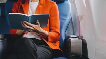 Attractive asian female passenger of airplane sitting in comfortable seat listening music in earphones while working at modern laptop computer with mock up area using wireless connection on board. video