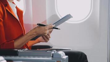 Attractive asian female passenger of airplane sitting in comfortable seat listening music in earphones while working at modern laptop computer with mock up area using wireless connection on board. video
