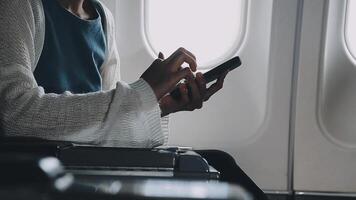 Woman hand using smart phone on airplane. Female traveler using smart phone in passenger cabin. Can be add your texts or others on screen. Sun shining trough airplane window. Technology concept. video