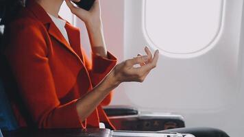 Attractive asian female passenger of airplane sitting in comfortable seat listening music in earphones while working at modern laptop computer with mock up area using wireless connection on board. video