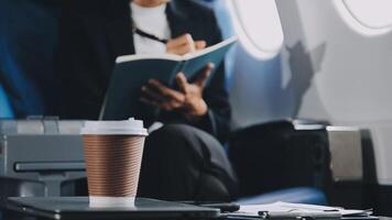 Attractive asian female passenger of airplane sitting in comfortable seat listening music in earphones while working at modern laptop computer with mock up area using wireless connection on board. video