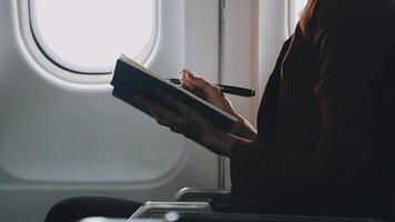 Attractive asian female passenger of airplane sitting in comfortable seat listening music in earphones while working at modern laptop computer with mock up area using wireless connection on board. video