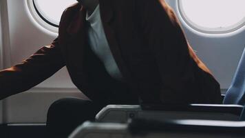 Attractive asian female passenger of airplane sitting in comfortable seat listening music in earphones while working at modern laptop computer with mock up area using wireless connection on board. video
