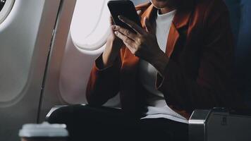 Woman hand using smart phone on airplane. Female traveler using smart phone in passenger cabin. Can be add your texts or others on screen. Sun shining trough airplane window. Technology concept. video