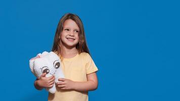 A smiling girl with healthy teeth holds a toy tooth and a toothbrush on a blue isolated background. A place for your text. Oral hygiene. Pediatric dentistry. Prosthetics. Rules for brushing teeth. photo