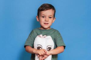 A smiling boy with healthy teeth holds a plush tooth on a blue background. Oral hygiene. Pediatric dentistry. photo