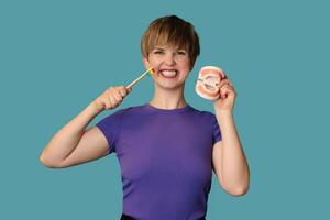 A close-up of a young woman with a model of a denture in her palm and a toothbrush in her hand on a blue background The concept of oral care. photo