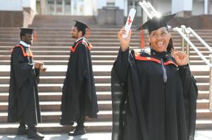 pretty african female college graduate at graduation with classmates photo
