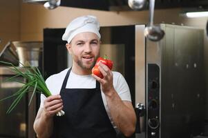 Portrait of a smiling male chef with cooked food standing in the kitchen photo